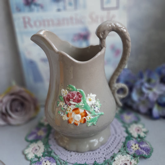 Decorative ceramic pitcher with floral design on a textured surface